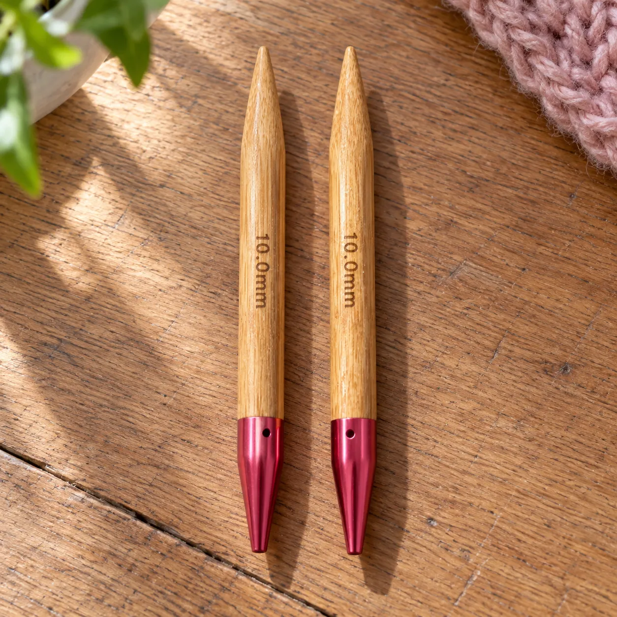 Detail of the two 10.0 mm bamboo needle tips with their pink metal ferrules. The complete set is shown in the lead image.
