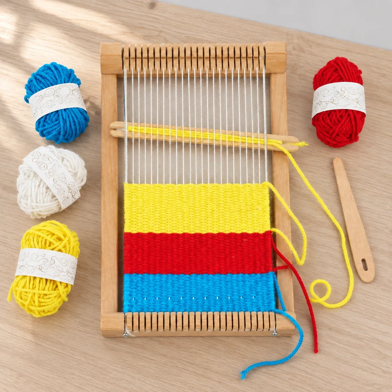 Complete loom with shuttle and red, blue, yellow and white yarn